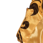 Custom gold muay thai shorts in shiny satin with Thai script embroidery and black side tribal panels